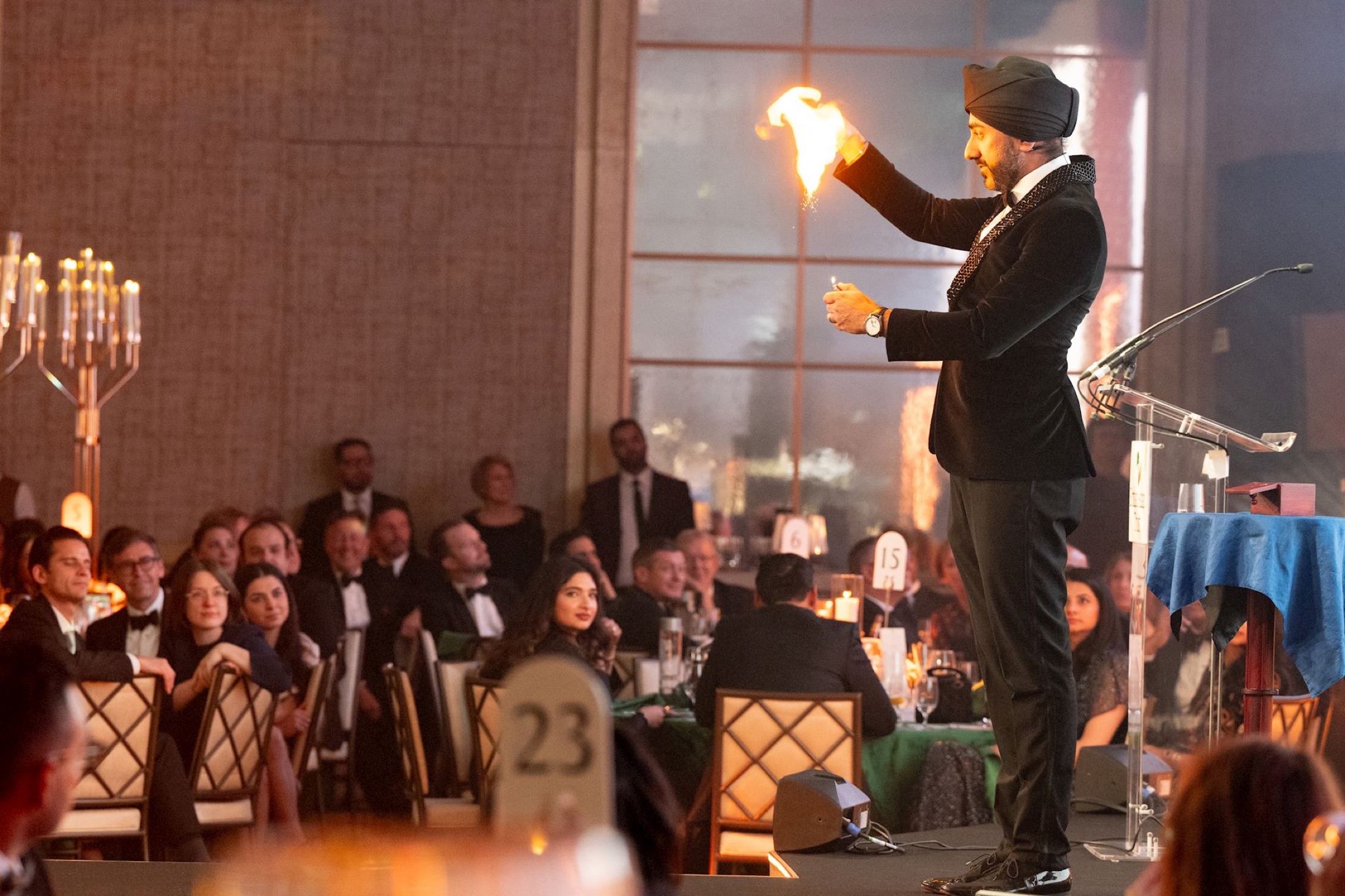 Magic Singh performing fire magic on stage at a black-tie event